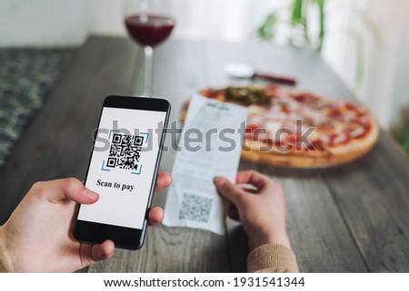Women's hands using the phone to scan the qr code to pay pizza. Scan to get discounts or pay for pizza. The concept of using a phone to transfer money or paying money online without cash.FAKE QR.