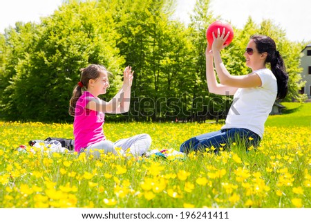 Mother and daughter throwing ball to each other in the park