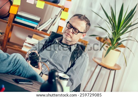 Designer in his office holding old camera