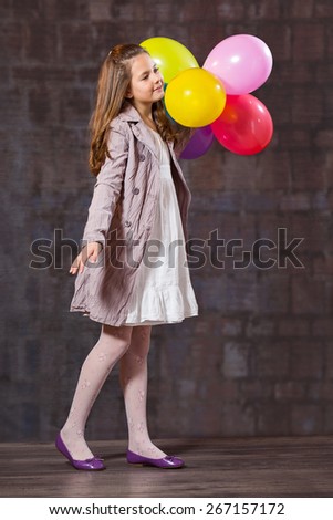 Ten year old caucasian girl with long hair posing in the studio with ballons