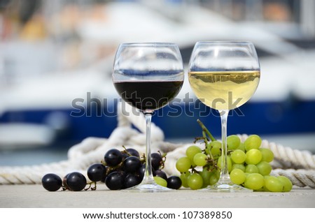 Pair of wineglasses and grapes against the yacht pier of La Spezia, Italy