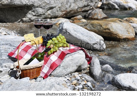 Red wine, cheese and grapes served at a picnic. Verzasca valley, Switzerland