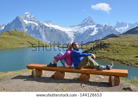 Travelers on a bench enjoying Alpine panorama. Jungfrau region, Switzerland