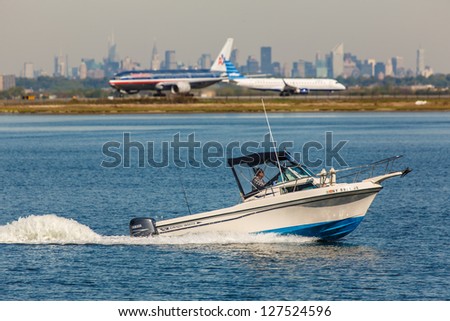 NEW YORK - December 8: Motor boat in Jamaica Bay with planes on JFK airport runway in background in New York USA on December 8, 2012 JFK airport is New York\'s main international airport opened in 1948