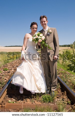 Bride and groom holding hands and flowers standing in rails