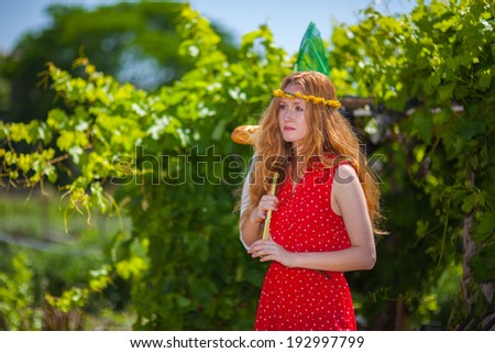 Pretty red-haired girl with curls  in nature  in red dress