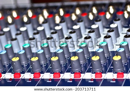 Wide angle photo of black sound mixer controller with knobs and sliders.