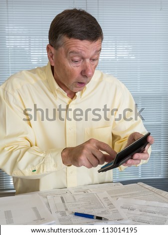 Senior caucasian man preparing tax form 1040 for tax year 2012  showing shock at amount of tax owed