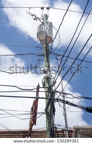 Complicated wiring forms tangled mess on power pole with light and camera