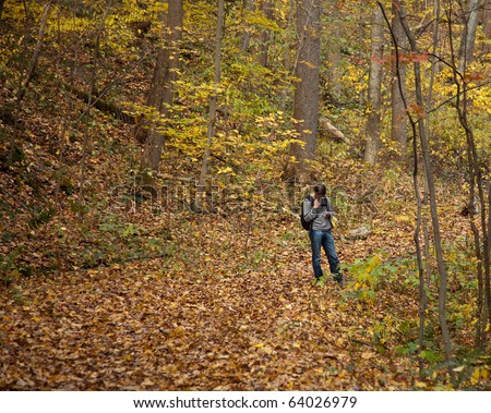Male walker checks handheld device for directions in leafy forest