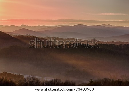Sun rising over snowy mountains of Smokies in early spring with fog in valleys