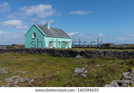 Light green painted small farmers agricultural home in south west Ireland or Eire. Stone built with slate roof and garden enclosed in solid stone walls