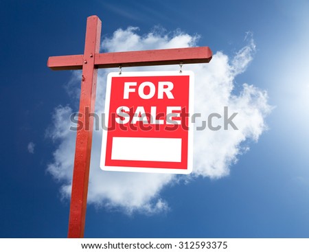 Realtor installed for sale sign for house or real estate set against blue sky and clouds