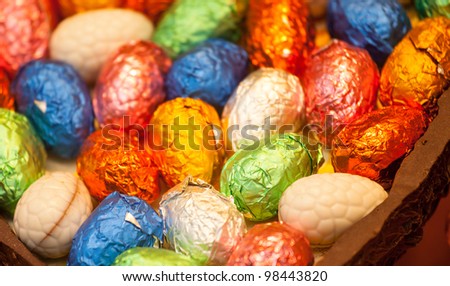 Multicolored foil wrapped easter eggs inside chocolate egg