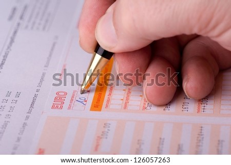 Hand of a man filling a bank transfer form.