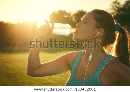 Drinking during sport / Young woman drinking water after run
