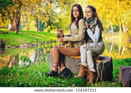 Friends in the park / Beautiful girlfriends are in the park with their dog, in autumn
