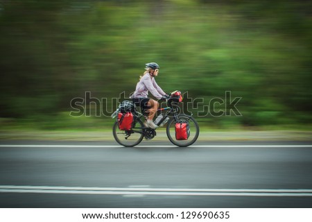A woman cycles fast along a road in New South Wales, Australia