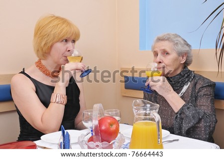 two happy women drinking wine and juice