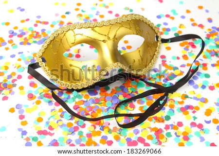 Golden carnival mask with ribbons on a confetti background
