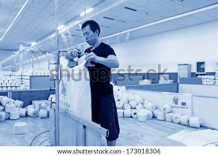 LUANNAN COUNTY, CHINA - DECEMBER 20: The workers were packing cotton reel thread in a production workshop, in the ZeAo spinning LTD., on December 20, 2013, Luannan county, hebei province, China.
