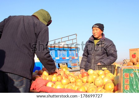 LUANNAN COUNTY - JANUARY 28: Customer and vendor in bargaining, before a fruit stalls, on january 28, 2014, Luannan county, Hebei province, China.