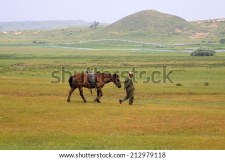 TULIGEN GRASSLAND - JULY 20: A Mongolian nomads on horseback, leisurely walk in the grasslands, in the Tuligen grassland on July 20, 2014, Inner Mongolia autonomous region, China.