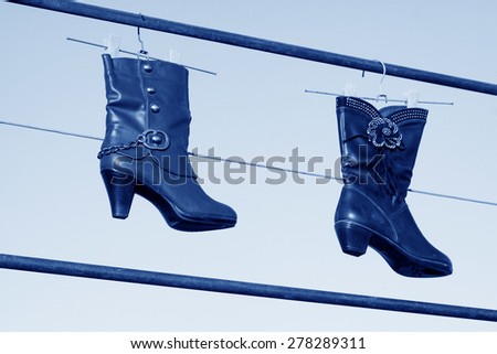 women\'s boots hanging in the blue sky, closeup of photo