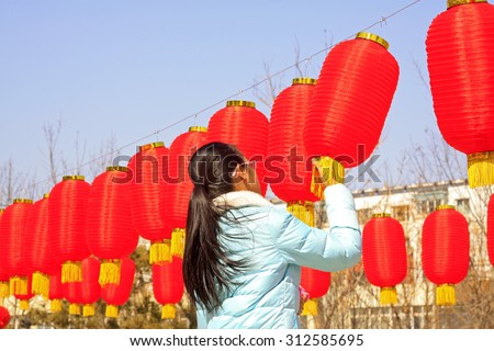 LUANNAN COUNTY - MARCH 5: On the Lantern Festival Day, A lady were busy with hanging red lanterns in a park, March 5, 2015, luannan county, hebei province, China