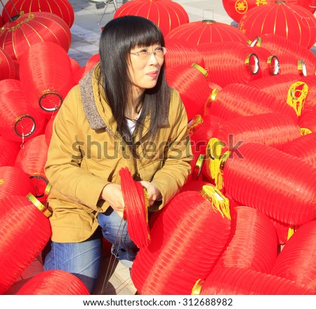LUANNAN COUNTY - MARCH 5: On the Lantern Festival Day, A lady was busy installing red lanterns in a park, March 5, 2015, luannan county, hebei province, China