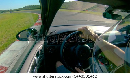 CLOSE UP: Man wearing a helmet races his fast car along the fun racetrack. Unrecognizable adrenaline seeking male race car driver having fun by driving his awesome sportscar along a closed track.