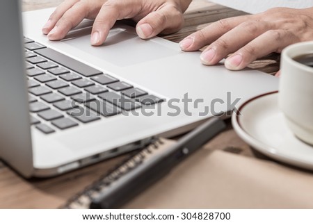 hand using laptop on office desk. Warm tone.