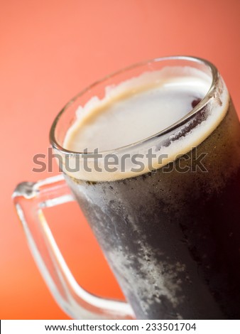 Closeup shot of root beer glass isolated on orange background