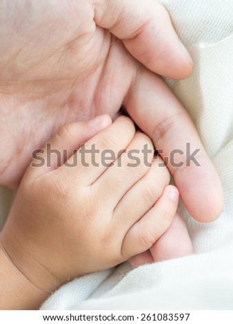 Parent and daughter holding hand together in concept of taking care of the little child
