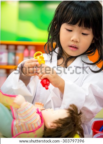 Adorable asian girl role playing doctor occupation wearing white gown uniform