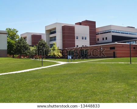 an exterior view of a college building with a large grass area in front of it