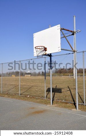 an old outdoor basketball backboard by a chain link fence