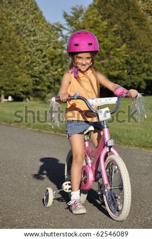 small girl on a bike with training wheels