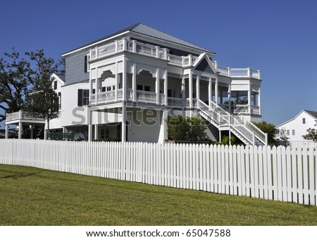 Large, two-story home with a white fence around the yard.