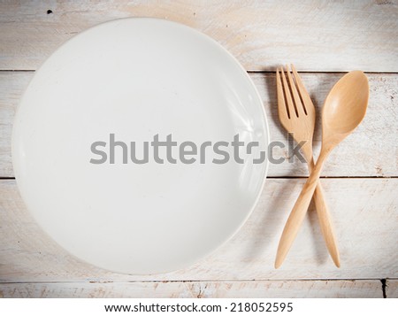 plate with fork and spoon on white wood