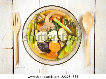 Fresh hot vegetable soup and spoon on wood