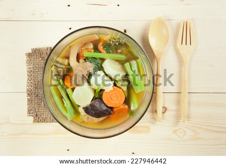 Fresh hot vegetable soup and spoon on wood