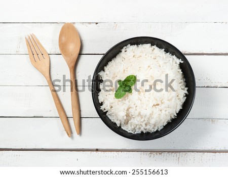 bowl full of rice and spoon on white wood