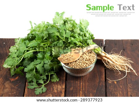 Coriander Leaves And Seeds in jars and on wood
