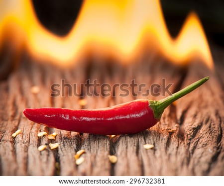 Red chili pepper with fire on wood