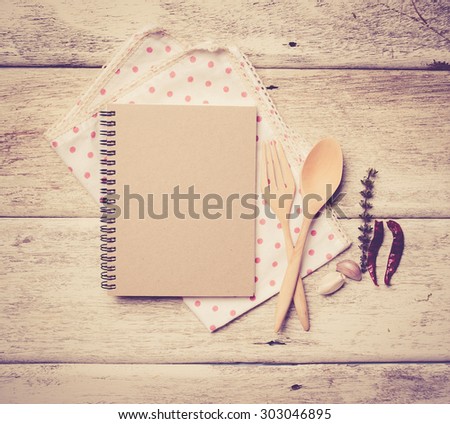 blank recipe book with wooden spoon and fresh herbs and spices on wooden background,vintage color toned image
