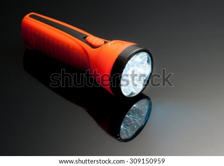 orange led lamps flashlight plastic body on reflected glass background