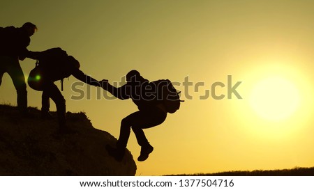 Climbers silhouettes stretch their hands to each other, climbing to the top of hill. travelers climb one after another on the rock. teamwork of business people. A team of businessmen is going to win. Stock foto © 