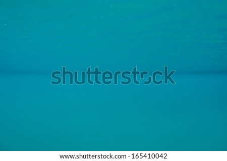 Clear blue sea water inside a western Pacific lagoon is mirrored in the calm surface. This image is from Mandarinfish Lake in the Republic of Palau in Micronesia.