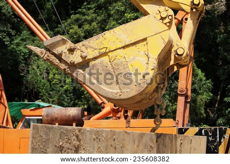 Bucket of Backhoe machine under removal of junk concrete at site.